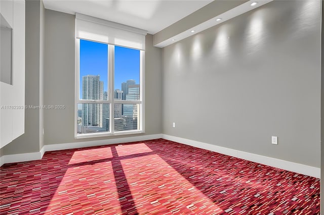 unfurnished room with recessed lighting, a view of city, and baseboards