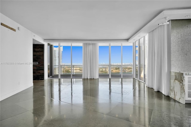 spare room with a wall of windows and baseboards