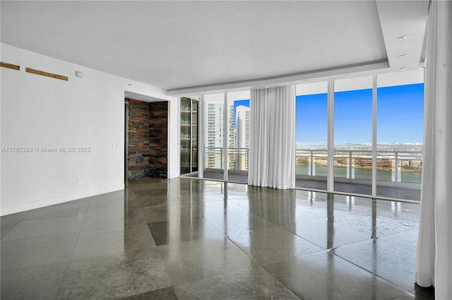 unfurnished room with a wealth of natural light, floor to ceiling windows, and baseboards