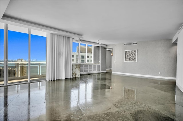 empty room featuring visible vents, floor to ceiling windows, plenty of natural light, and baseboards