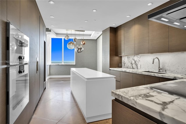 kitchen with a sink, a kitchen island, modern cabinets, and light countertops