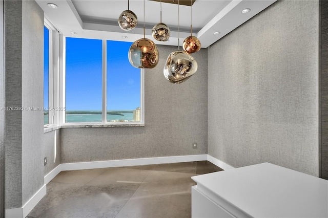 interior space featuring a tray ceiling, recessed lighting, and baseboards