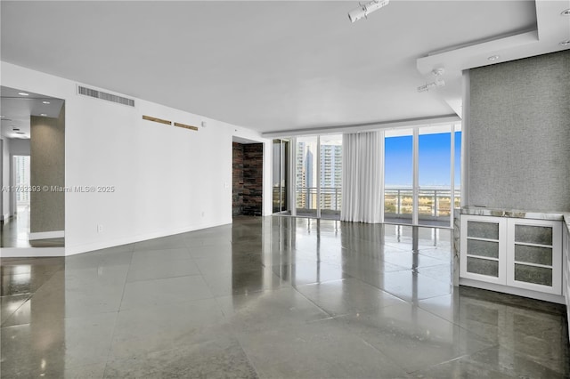 unfurnished room featuring visible vents, baseboards, and expansive windows