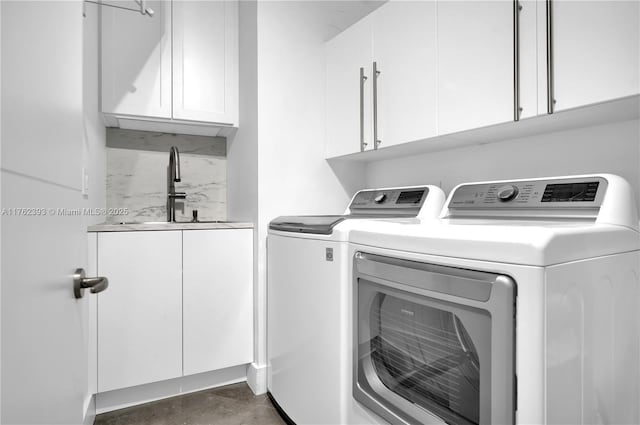 washroom with washer and dryer, wet bar, cabinet space, and a sink