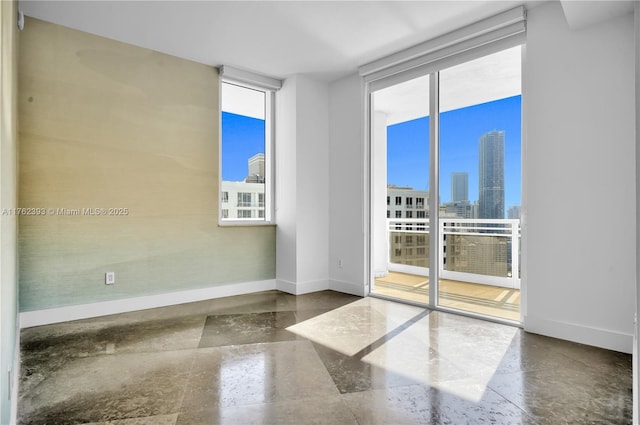 unfurnished room featuring expansive windows, baseboards, and a city view