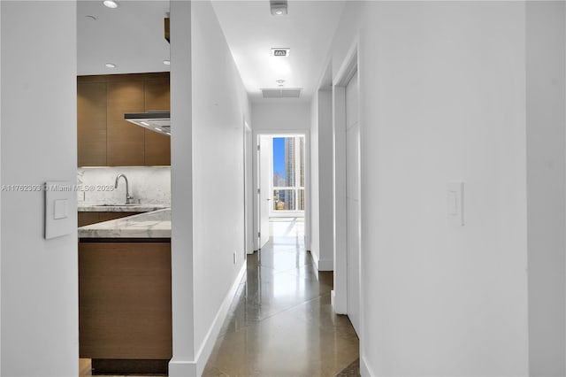 hall with baseboards, visible vents, and a sink