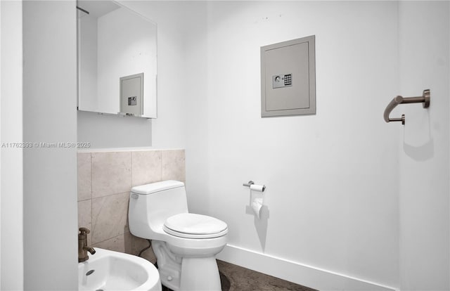 half bath featuring tile walls, toilet, and a bidet