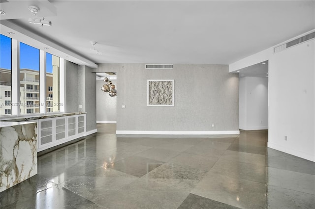 unfurnished room featuring granite finish floor, baseboards, and visible vents