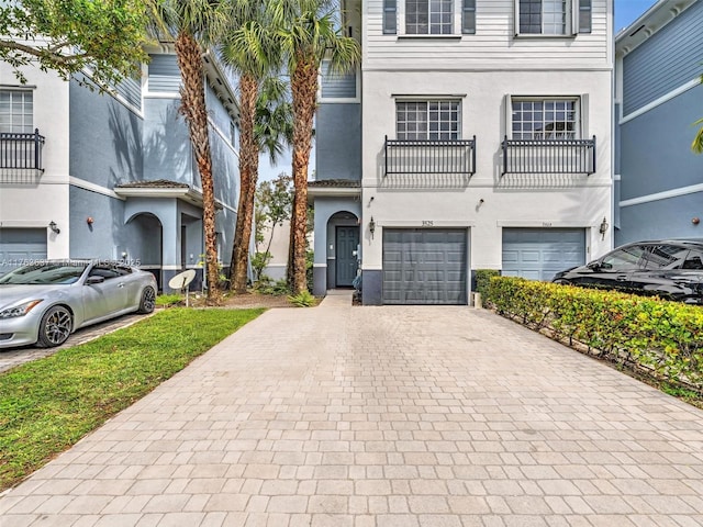 view of front of property featuring decorative driveway, an attached garage, and stucco siding