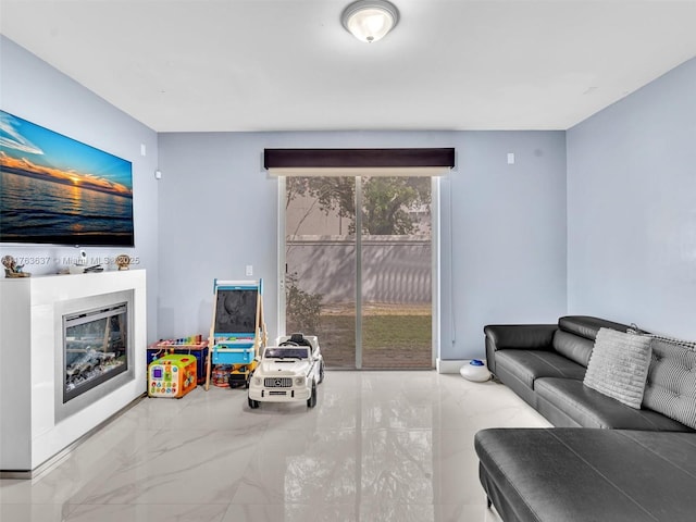 living area with a glass covered fireplace and marble finish floor