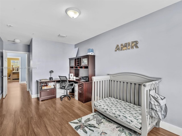 bedroom featuring visible vents, baseboards, and wood finished floors