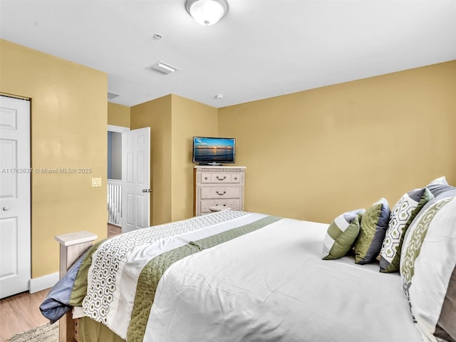 bedroom with visible vents, baseboards, and wood finished floors