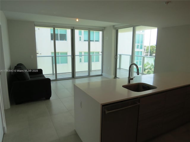 kitchen featuring a sink, light tile patterned floors, a center island with sink, and light countertops