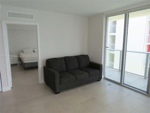 living room with light tile patterned floors, visible vents, and expansive windows