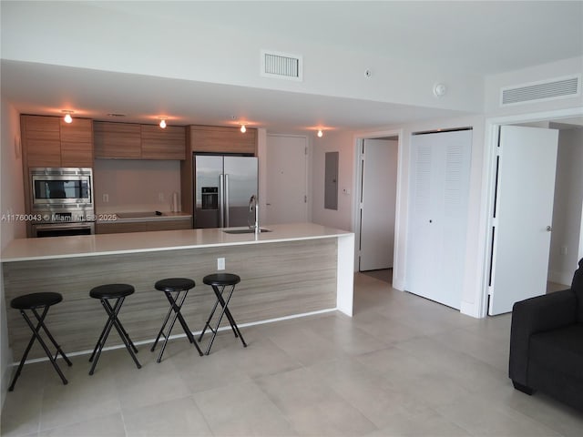 kitchen with brown cabinetry, visible vents, stainless steel appliances, and modern cabinets