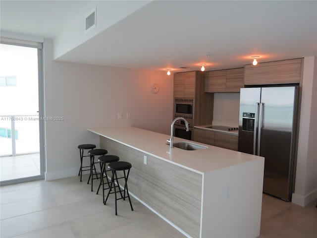 kitchen featuring visible vents, a sink, appliances with stainless steel finishes, modern cabinets, and brown cabinets