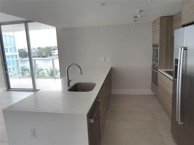 kitchen with modern cabinets, a sink, appliances with stainless steel finishes, a peninsula, and light countertops