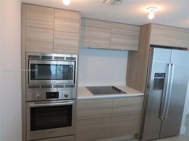 kitchen with visible vents, modern cabinets, light brown cabinets, stainless steel appliances, and light countertops