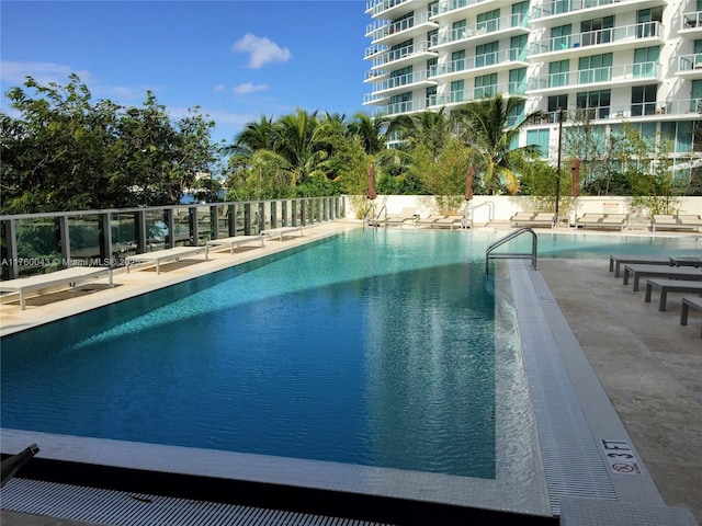 community pool with a patio area and fence