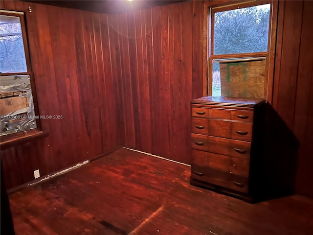 unfurnished bedroom featuring dark wood finished floors and wooden walls