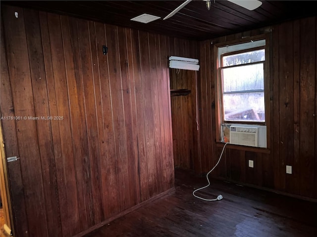 empty room with cooling unit, wood finished floors, wood walls, and ceiling fan