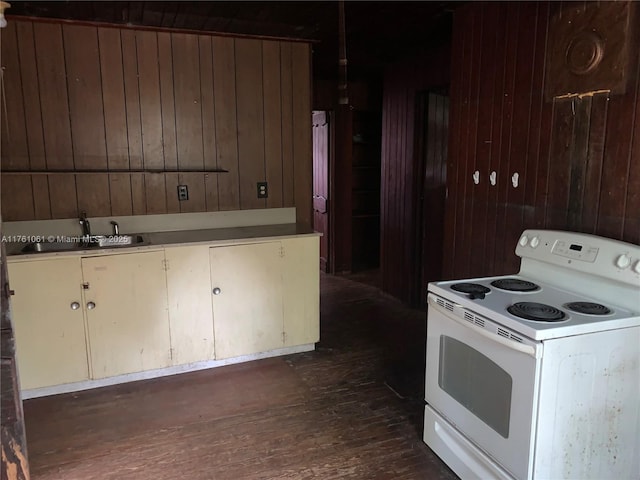 kitchen featuring dark wood-type flooring, wooden walls, white electric range, and a sink