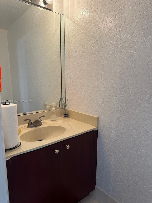 bathroom featuring vanity and a textured wall