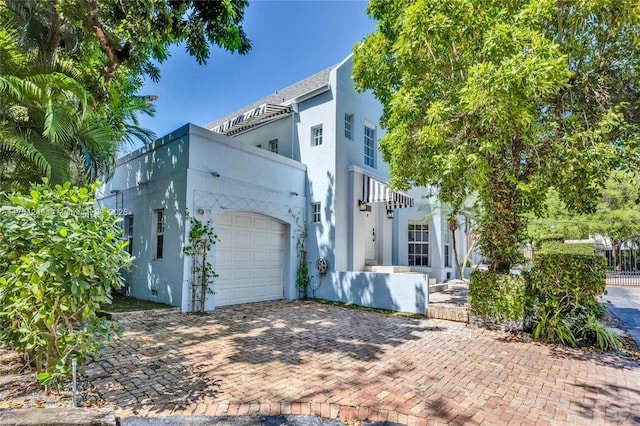 view of front of home with stucco siding, decorative driveway, and a garage