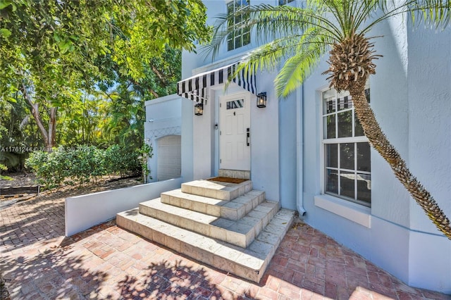 doorway to property featuring an attached garage and stucco siding