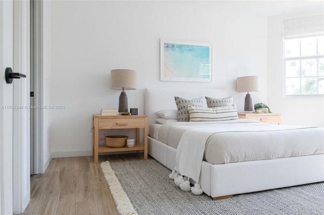 bedroom featuring light wood finished floors and baseboards