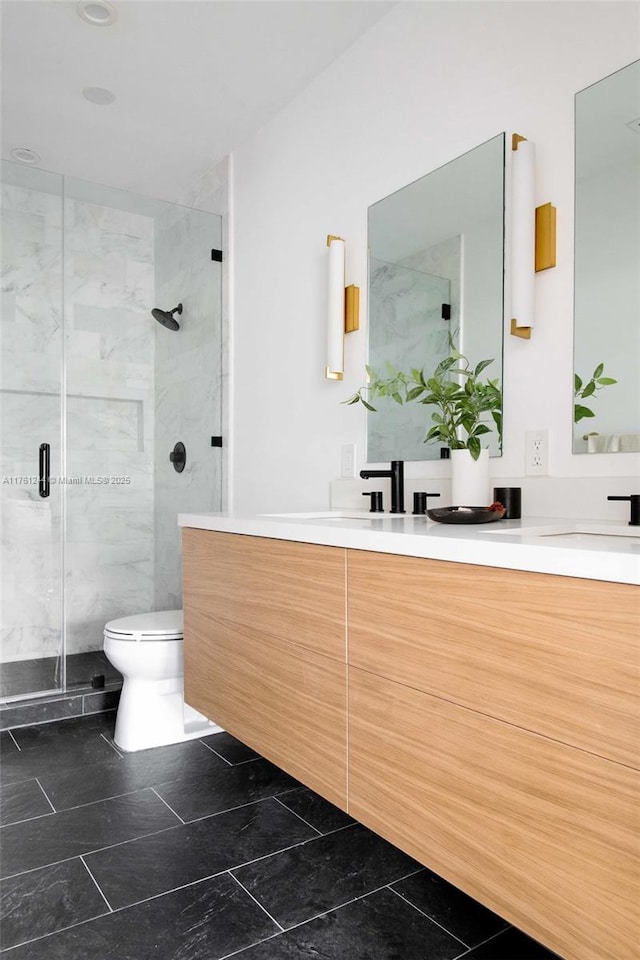 full bathroom featuring double vanity, toilet, a shower stall, and a sink