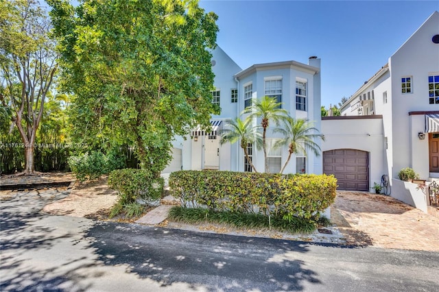 view of front facade featuring decorative driveway, a garage, and stucco siding