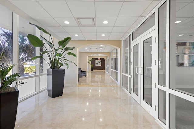 hallway with recessed lighting, arched walkways, french doors, and a paneled ceiling