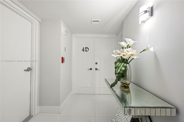 corridor with light tile patterned floors, visible vents, and baseboards