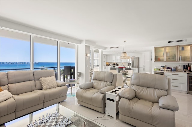 living area featuring light tile patterned flooring, wine cooler, indoor bar, and a water view