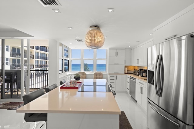 kitchen featuring visible vents, a water view, a kitchen island, white cabinetry, and appliances with stainless steel finishes