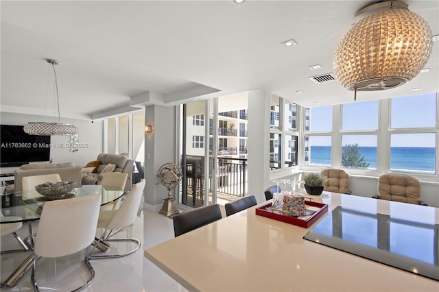 dining space featuring tile patterned floors, a notable chandelier, visible vents, and a water view