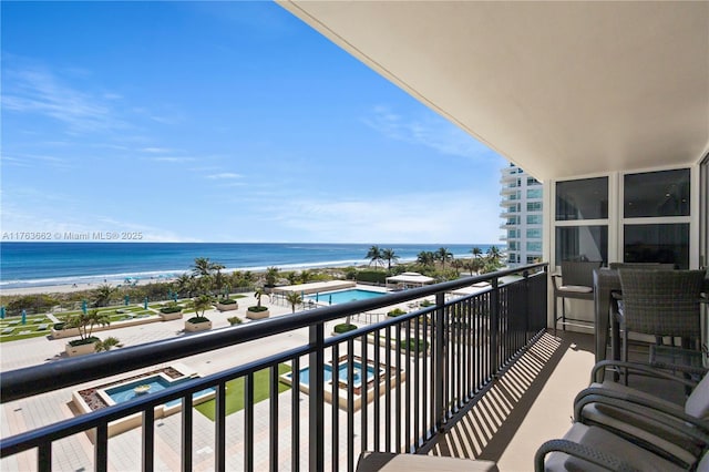 balcony featuring a view of the beach and a water view