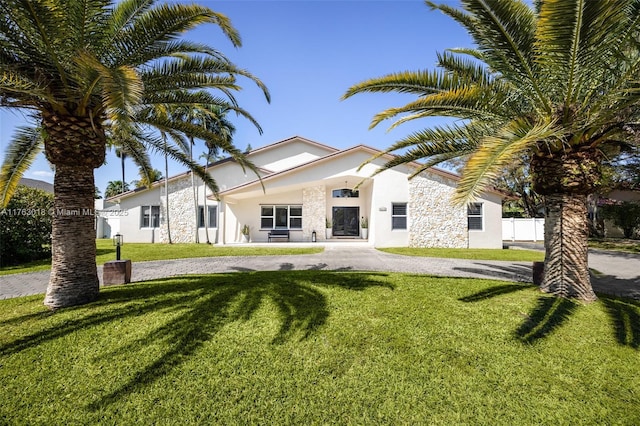 rear view of house featuring a lawn, fence, and stucco siding