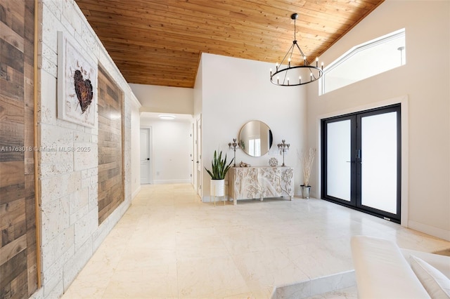 foyer entrance with a high ceiling, wood ceiling, french doors, a notable chandelier, and marble finish floor