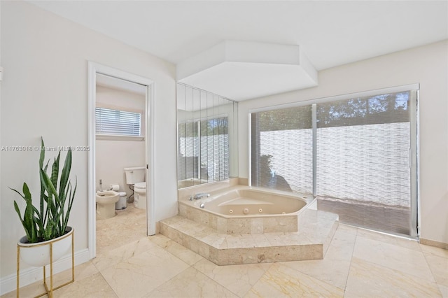 full bathroom featuring baseboards, a bidet, toilet, and a jetted tub