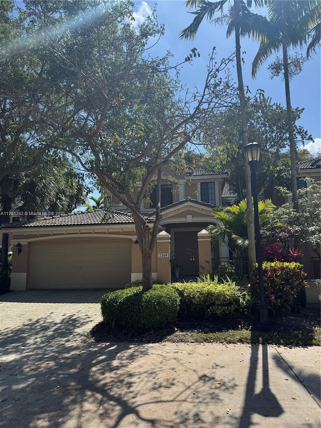 view of front of house with a garage, driveway, stucco siding, and a tile roof