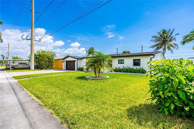 ranch-style house with a front yard, an attached garage, concrete driveway, and stucco siding