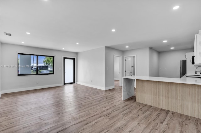 kitchen with visible vents, light countertops, freestanding refrigerator, light wood-style floors, and a sink