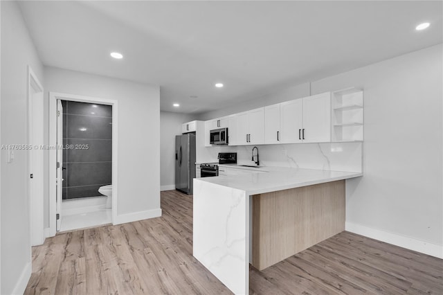 kitchen featuring a sink, open shelves, light wood finished floors, and stainless steel appliances