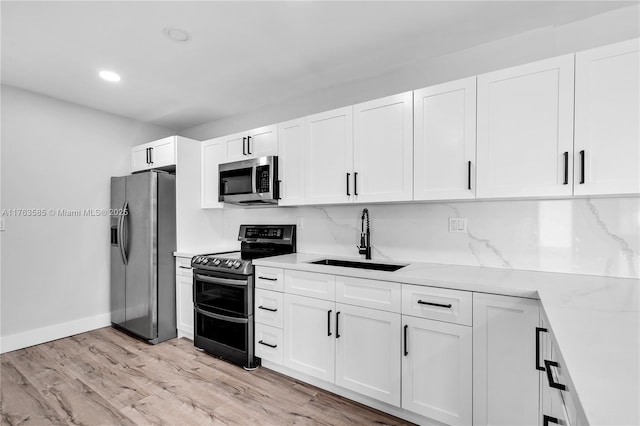 kitchen featuring a sink, stainless steel appliances, white cabinets, and light wood finished floors