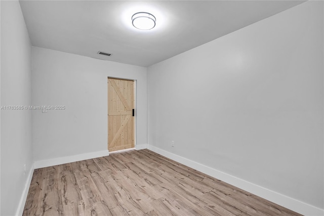 spare room featuring visible vents, baseboards, and wood finished floors