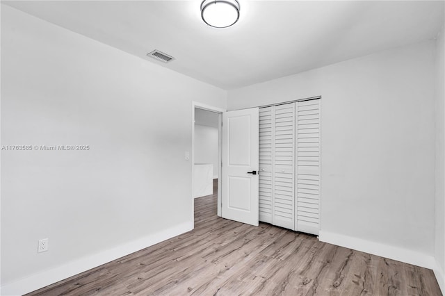 unfurnished bedroom with visible vents, baseboards, a closet, and wood finished floors