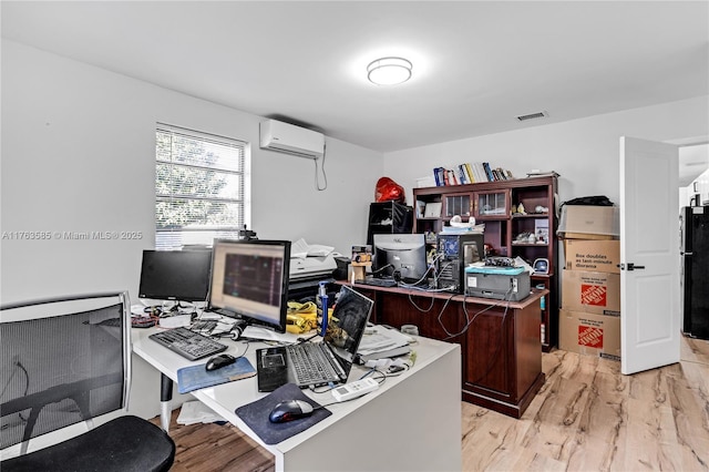 office featuring light wood-type flooring, visible vents, and a wall mounted AC