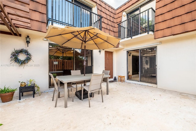 view of patio with a balcony and outdoor dining space